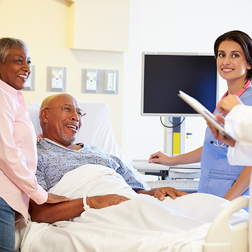 Medical consultant and team speaking to elderly patient