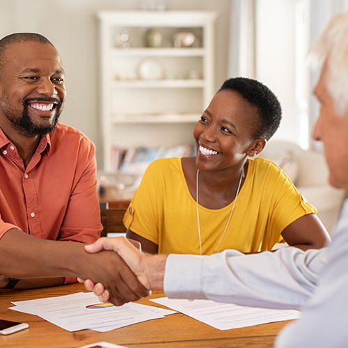 Professional couple shaking hands with a third person