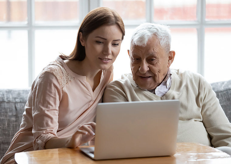 Young woman helping and eldery man on a laptop computer